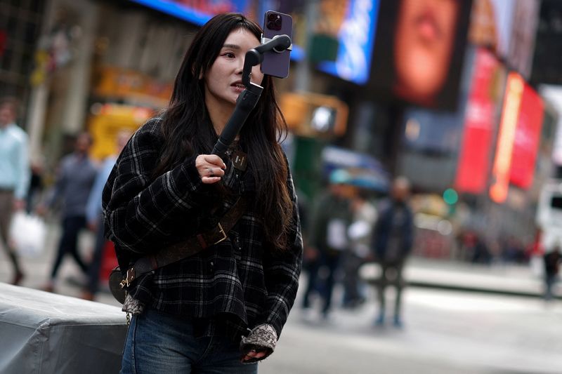 © Reuters. A woman makes a video to post on TikTok, Times Square, New York City, March 13, 2024. REUTERS/Mike Segar