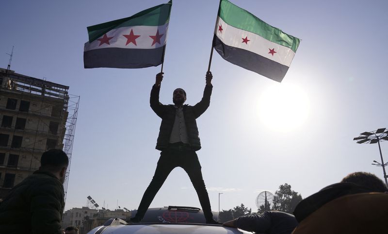 &copy; Reuters. A man holds the Syrian opposition flag as they celebrate after Syria's army command notified officers on Sunday that President Bashar al-Assad's 24-year authoritarian rule has ended, a Syrian officer who was informed of the move told Reuters, following a 