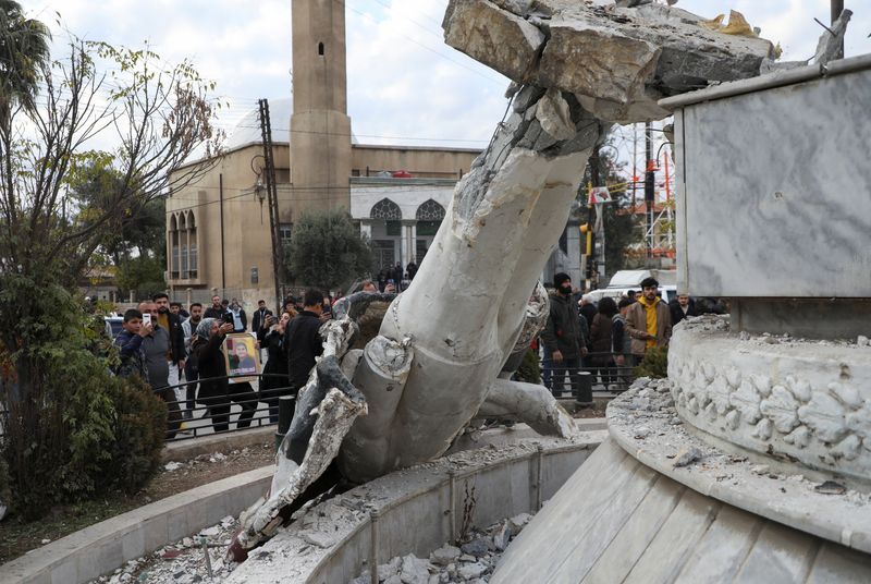 &copy; Reuters. People stand near a damaged statue of former Syrian president Hafez al-Assad after Syrian rebels announced that they have ousted President Bashar al-Assad, in Qamishli, Syria December 8, 2024. REUTERS/Orhan Qereman