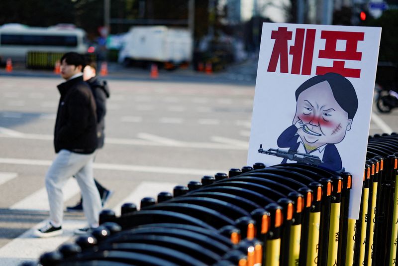 &copy; Reuters. A pedestrian walks past a banner denouncing South Korean President Yoon Suk Yeol, who declared martial law, which was reversed hours later, in front of the National Assembly in Seoul, South Korea, December 9, 2024. The slogan reads, 'arrest'. REUTERS/Kim 