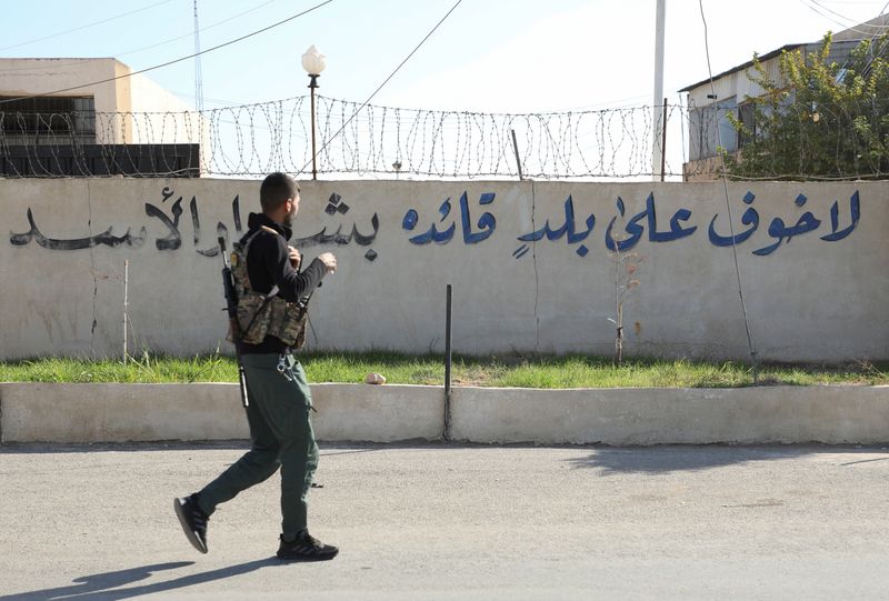 &copy; Reuters. A member of the Kurdish-led Syrian Democratic Forces (SDF) walks near a writing on a wall that reads, "There is no fear for a country whose leader is Bashar al-Assad", after rebels seized the capital and ousted Syria's Bashar al-Assad in Damascus, in Qami