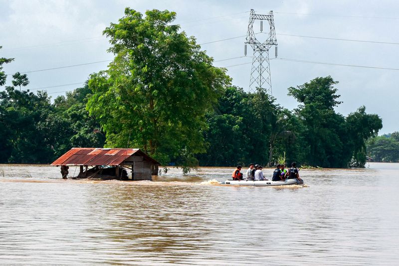 © Reuters. FILE PHOTO: Volunteers ride a boat through a flooded area, searching for people stranded following the impact of Typhoon Yagi in Taungnu city, Myanmar, September 17, 2024. REUTERS/Stringer/File Photo