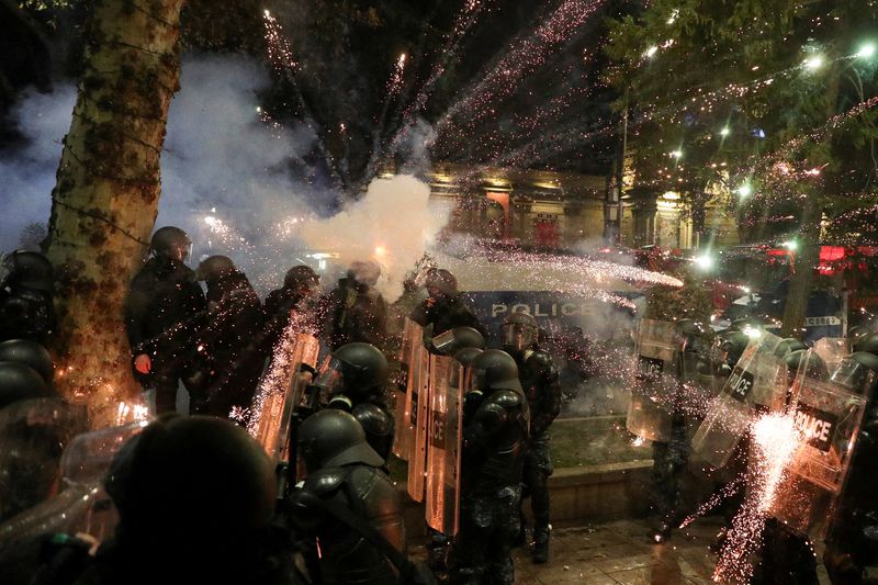 © Reuters. A firework explodes near police officers during a rally of opposition parties' supporters, who protest against the new government's decision to suspend the European Union accession talks and refuse budgetary grants until 2028, in Tbilisi, Georgia November 30, 2024. REUTERS/Irakli Gedenidze/File Photo