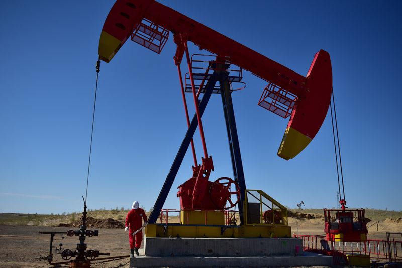 &copy; Reuters. Un operaio di PetroChina ispeziona un martinetto in un giacimento petrolifero a Tacheng, nella regione autonoma di Xinjiang Uighur, in Cina, il 27 giugno 2018. REUTERS/Stringer