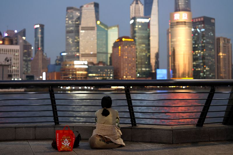 © Reuters. A woman sits on the Bund near Huangpu river as she looks on the financial district of Pudong in Shanghai, China September 27, 2024. REUTERS/Tingshu Wang/File Photo