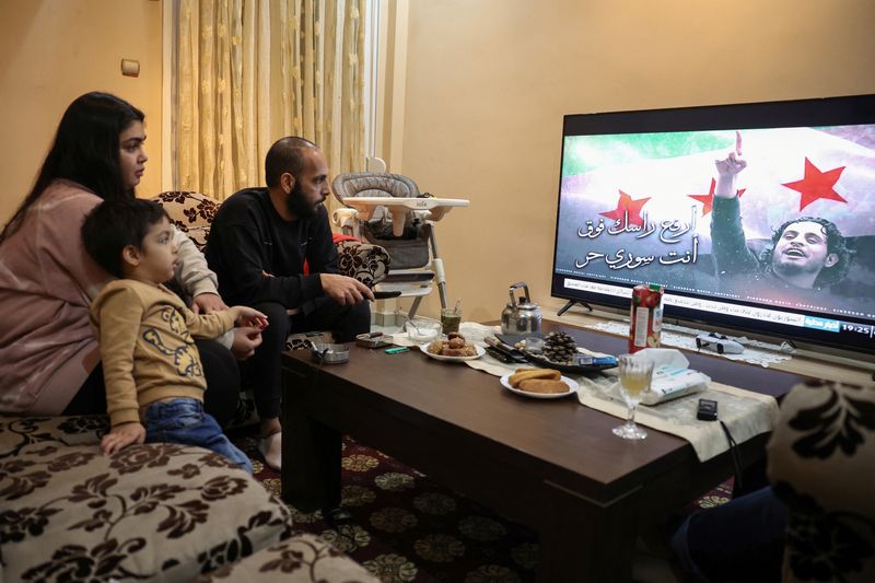 &copy; Reuters. Syrian refugees, Najem Al Moussa, 36, his wife Bushra Al Bukaai, 30, and their youngest son, Oday, 3, watch news on the events in Syria in their apartment in Athens, Greece, December 10, 2024. REUTERS/Louisa Gouliamaki