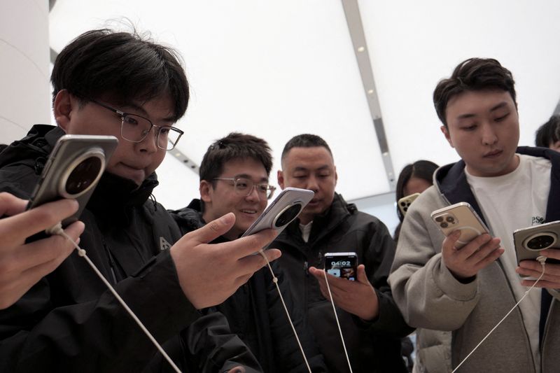 &copy; Reuters. FILE PHOTO: Visitors look at Huawei's newly unveiled Mate 70 smartphone series at a flagship store in Beijing, China November 26, 2024.  REUTERS/Xiaoyu Yin/File Photo