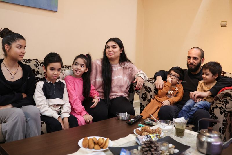 © Reuters. Syrians Najem Al Moussa, 36, his wife Bushra Al Bukaai, 30, and their 5 children, Mira ,13, Tzias, 9, Eman, 7, Eyas, 5, and Oday, 3, joke while posing in their home in Athens, Greece, December 10, 2024. REUTERS/Louisa Gouliamaki