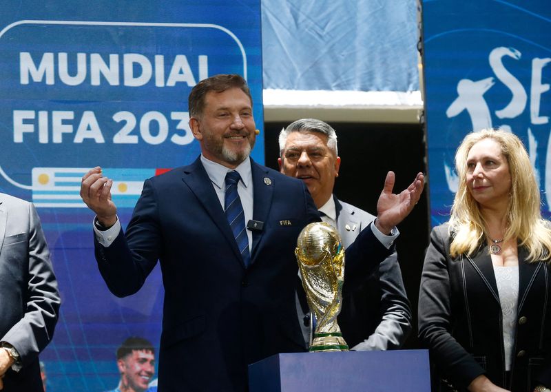 © Reuters. Soccer Football - CONMEBOL ratifies the hosting of the 2030 World Cup opening matches in South America - Asuncion, Paraguay - December 11, 2024 CONMEBOL president Alejandro Dominguez, Argentine Football Association president Claudio Tapia and Argentina General Secretary of the Presidency Karina Milei, posing with a replica of the World Cup during the announcement REUTERS/Cesar Olmedo