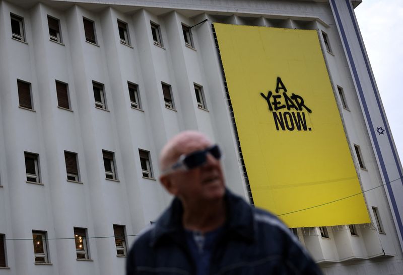 © Reuters. A man walks past a banner that was made for the one-year anniversary of the deadly October 7, 2023 attack by Hamas, in Tel Aviv, Israel, December 11, 2024. REUTERS/Stoyan Nenov