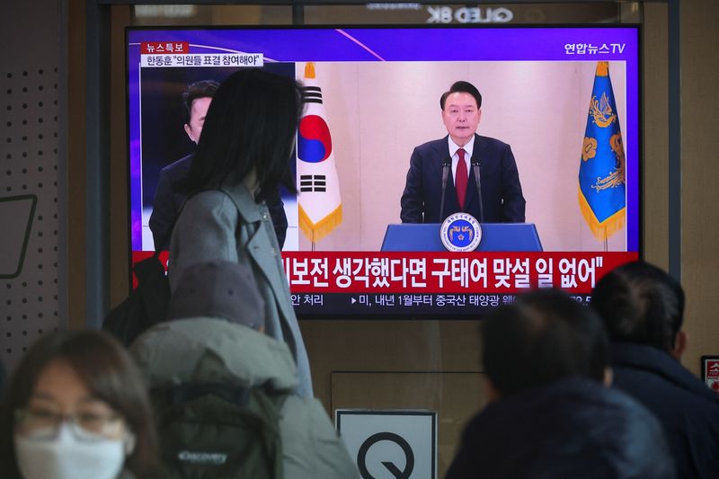 © Reuters. People watch a TV screen, broadcasting South Korean President Yoon Suk Yeol delivering an address to the nation, at a railway station in Seoul, South Korea, December 12, 2024. REUTERS/Kim Hong-Ji