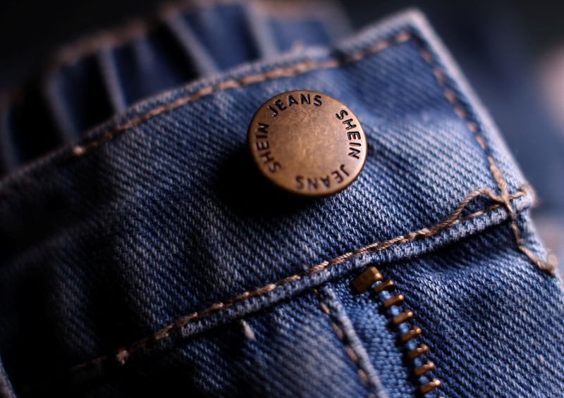 © Reuters. A Shein logo is pictured on the button of a pair of the company’s jeans in Manchester, Britain, December 11, 2024. REUTERS/Phil Noble/File Photo