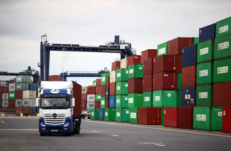 © Reuters. FILE PHOTO: A truck drives past stacked shipping containers at the port of Felixstowe, Britain, October 13, 2021. REUTERS/Hannah McKay/File Photo