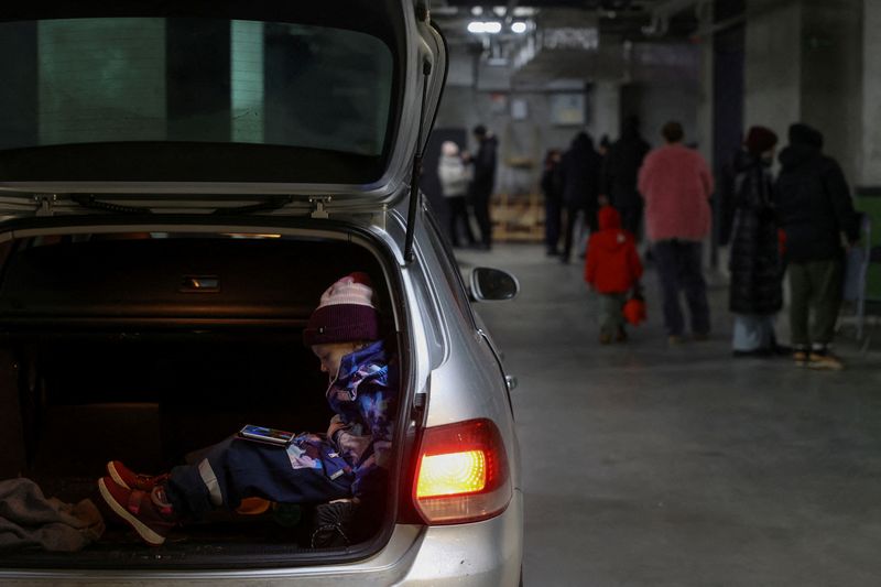 © Reuters. People take a shelter inside an underground parking of an apartment building during a massive Russian missile attack across a country, in Lviv, Ukraine December 13, 2024. REUTERS/Roman Baluk 