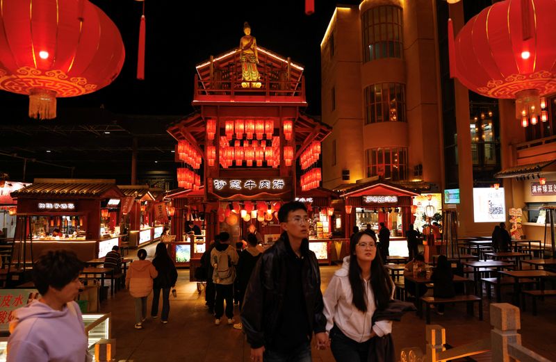 © Reuters. FILE PHOTO: People walk at a night market, during an organised media tour to Dunhuang, Gansu province, China October 15, 2024. REUTERS/Tingshu Wang/File Photo