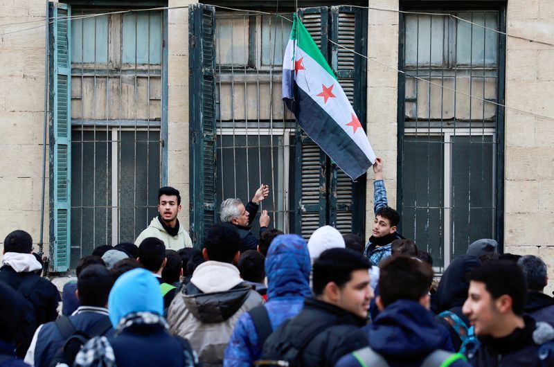 &copy; Reuters. A teacher hoists the flag adopted by the new Syrian rulers at a school in the early morning, following an announcement of the reopening of schools by the authorities, after the ousting of Syria’s Bashar al-Assad, in Damascus, Syria December 15, 2024. RE