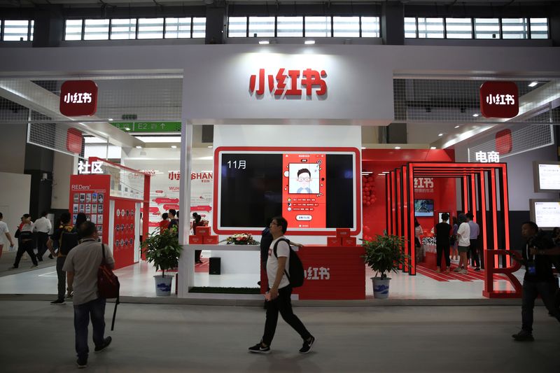 © Reuters. FILE PHOTO: A man walks past the booth of Chinese startup Xiaohongshu, meaning 