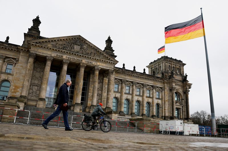 © Reuters. A cyclist and a pedestrian pass by the Reichstag building as the German national flag flutters, on the day of a confidence vote called by German Chancellor Olaf Scholz to pave way for snap election, in Berlin, Germany, December 16, 2024. REUTERS/Lisi Niesner