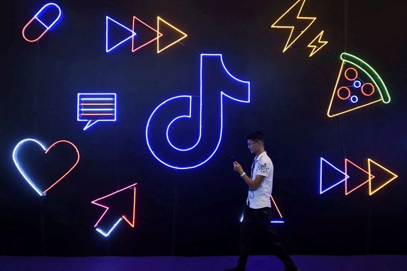 &copy; Reuters. FILE PHOTO: A man holding a phone walks past a sign of Chinese company ByteDance's app TikTok, known locally as Douyin, at the International Artificial Products Expo in Hangzhou, Zhejiang province, China October 18, 2019. REUTERS/Stringer/File Photo