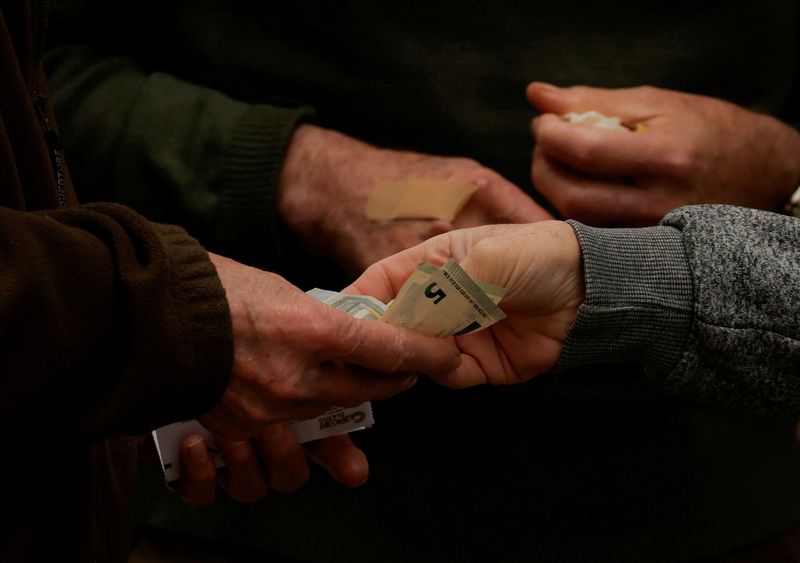 © Reuters. FILE PHOTO: A customer pays a street lottery seller with five-euro notes, in Ronda, Spain, May 14, 2024. REUTERS/Jon Nazca/File Photo