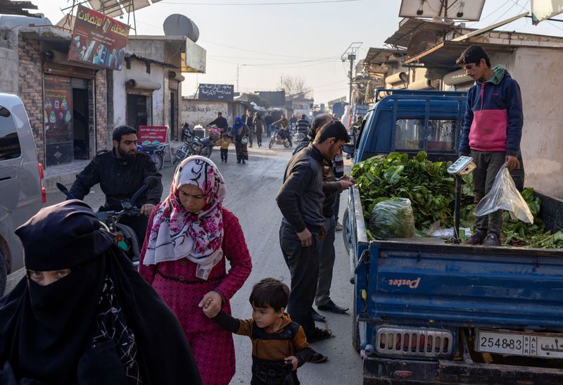 © Reuters. People walk along a street in a refugee camp in Idlib, a town in northwest Syria where Hayat Tahrir al-Sham (HTS) had maintained an administration when the front lines of the Syrian civil war were frozen, Syria, December 17, 2024. REUTERS/ Umit Bektas