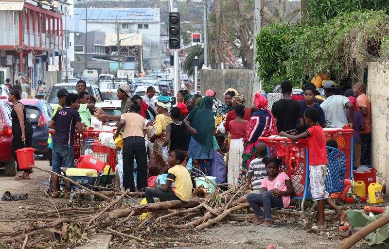 © Reuters. People queue to fill containers with driking water in the aftermath of Cyclone Chido, in Doujani, Mayotte, France, December 18, 2024. REUTERS/Yves Herman