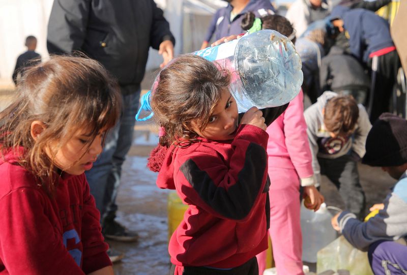 &copy; Reuters. Una ragazza palestinese trasporta un contenitore d'acqua, mentre i palestinesi sono in attesa di prendere dell'acqua, in seguito a un rapporto di Human Rights Watch che afferma che la privazione dell'acqua da parte di Israele a Gaza è un atto di genocidi