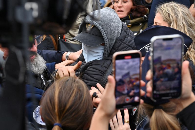 &copy; Reuters. A man hiding his face is surrounded by French police, journalists and protesters as he leaves after the verdict in the trial for Dominique Pelicot, a Frenchman accused of drugging his then-wife Gisele Pelicot and recruiting dozens of strangers to rape her