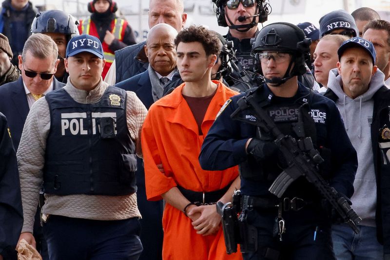 © Reuters. Luigi Mangione, the suspect in the murder of UnitedHealth Group executive Brian Thompson, arrives at a helicopter pad after being extradited from Pennsylvania, as New York Mayor Eric Adams walks behind him, in New York, U.S., December 19, 2024. REUTERS/Eduardo Munoz