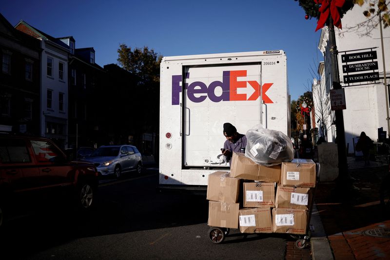 © Reuters. FILE PHOTO: A FedEx driver stands with packages near a delivery truck during preparations for Black Friday in the Georgetown neighborhood of Washington, U.S., November 26, 2024. REUTERS/Benoit Tessier/File Photo