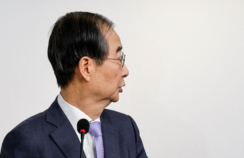 © Reuters. FILE PHOTO: South Korean Prime Minister Han Duck-soo speaks alongside ruling People Power Party leader Han Dong Hoon (not pictured) as they release a joint public statement after the impeachment vote against the president failed, at the party's headquarters in Seoul, South Korea, December 8, 2024. REUTERS/Kim Kyung-Hoon/File Photo