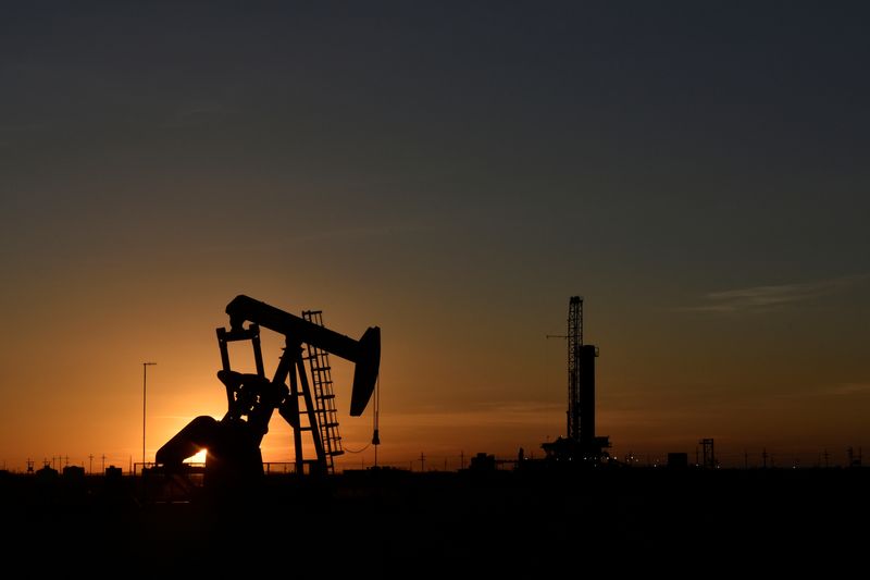 © Reuters. FILE PHOTO: A pump jack operates in front of a drilling rig at sunset in an oil field in Midland, Texas U.S. August 22, 2018. Picture taken August 22, 2018. REUTERS/Nick Oxford/File Photo