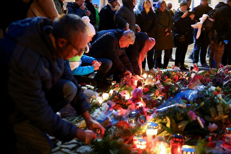 © Reuters. People leave candles and flowers in tribute to the victims near the site where a car plowed into a crowd of people at the Magdeburg Christmas market in Magdeburg, Germany on December 21, 2024. REUTERS/Christian Mang