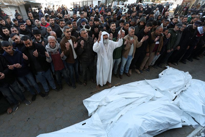 © Reuters. Mourners pray during the funeral of Palestinians killed in an Israeli raid, amid the ongoing conflict between Israel and Hamas, at Al-Aqsa Martyrs Hospital, in Deir al-Balah, central Gaza Strip, December 22, 2024. REUTERS/Ramadan Abed