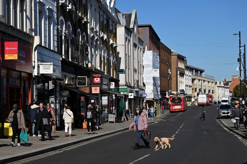 © Reuters. FILE PHOTO: A woman walks across the road with her dog on the high street of Richmond, in London, Britain, October 11, 2024. REUTERS/Jaimi Joy/File photo