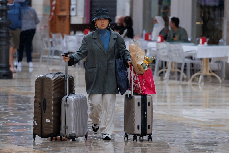 &copy; Reuters. A tourist pushes suitcases as she walks along a shopping street in central Malaga, Spain, April 28, 2022. REUTERS/Jon Nazca