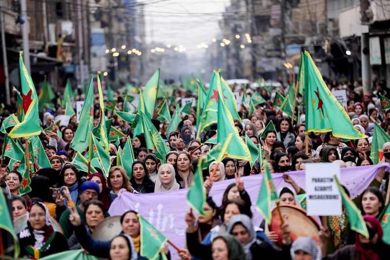 © Reuters. Women hold Women's Protection Units (YPJ) flags during a rally demanding the new Islamist rulers in Damascus respect women's rights and condemn Turkish-backed military campaigns in Kurdish-led regions of the north, in the northeastern city of Qamishli, Syria, December 23, 2024. REUTERS/Orhan Qereman