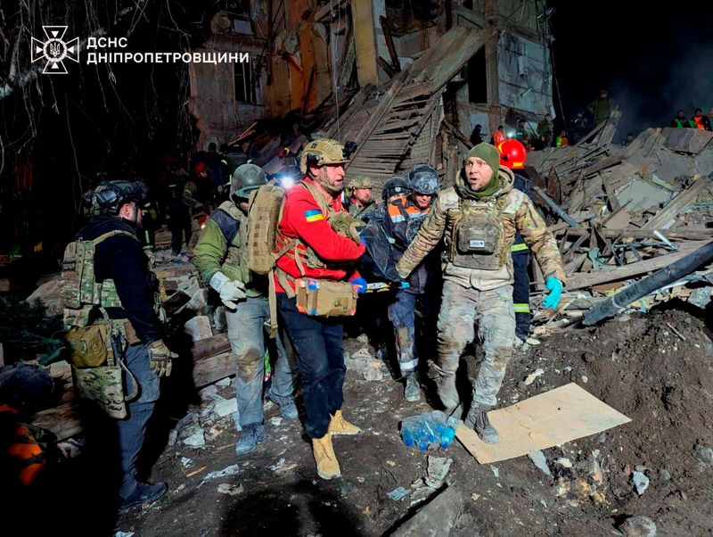 © Reuters. Rescuers carry the body of a killed person at the site where an apartment building was hit by a Russian missile strike, amid the Russian attack on Ukraine, in Kryvyi Rih, Ukraine on December 24, 2024. Press service of the Ukrainian State Emergency Service in Dnipropetrovsk region/Handout via Reuters