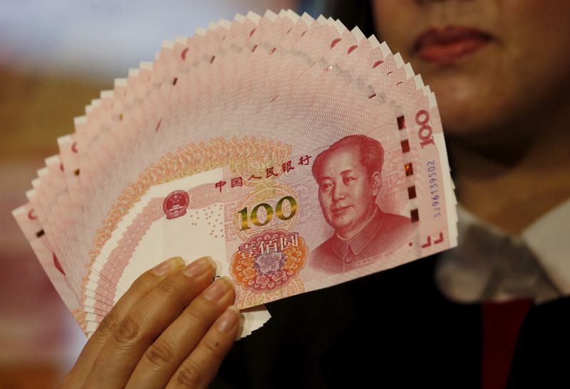 © Reuters. FILE PHOTO: An employee poses with the 2015 edition of the 100 renminbi banknotes at the Bank of China Tower in Hong Kong, China, November 12, 2015. REUTERS/Bobby Yip/File Photo