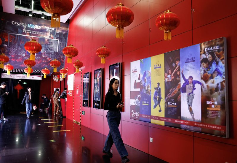 © Reuters. FILE PHOTO: A person walks past movie posters at the Capital Cinema in Beijing, China February 21, 2024. REUTERS/Tingshu Wang/File Photo