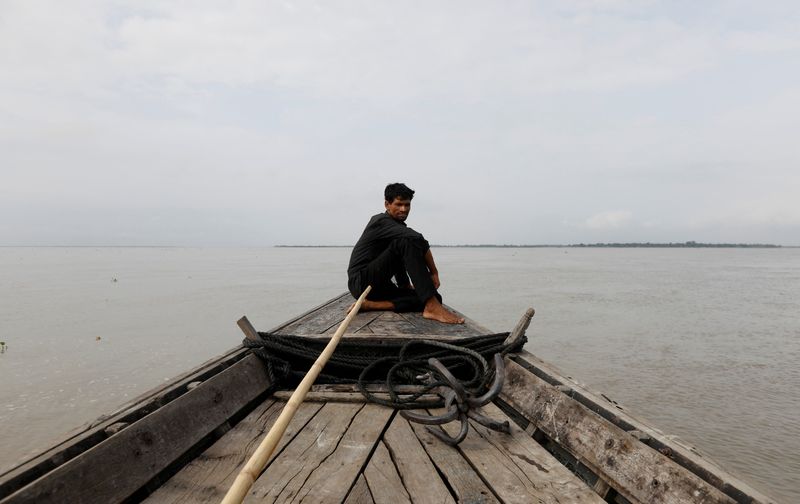 © Reuters. FILE PHOTO: A man sits in a boat on the waters of the Brahmaputra river near the international border between India and Bangladesh in Dhubri district, in the northeastern state of Assam, India August 4, 2018.  REUTERS/Adnan Abidi/File Photo