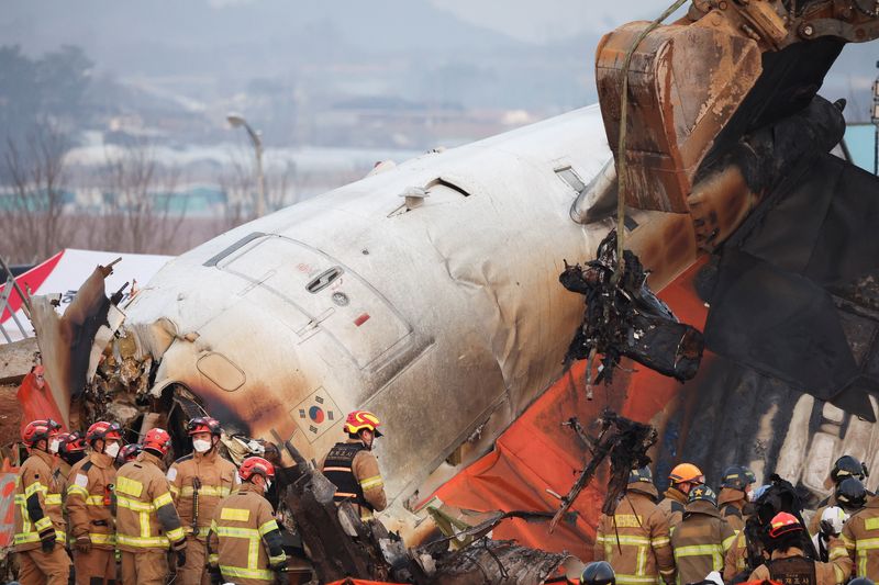 © Reuters. An excavator is used to lift burnt chairs from the wreckage of an aircraft that crashed after it went off the runway at Muan International Airport, in Muan, South Korea, December 29, 2024. REUTERS/Kim Hong-Ji