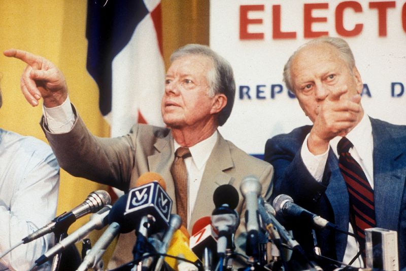 © Reuters. FILE PHOTO: Former U.S. Presidents Jimmy Carter and Gerald Ford point in different directions while calling on reporters wanting to ask questions at a press conference in Panama City, Panama, May 5, 1989.  REUTERS/Dematteis/File Photo