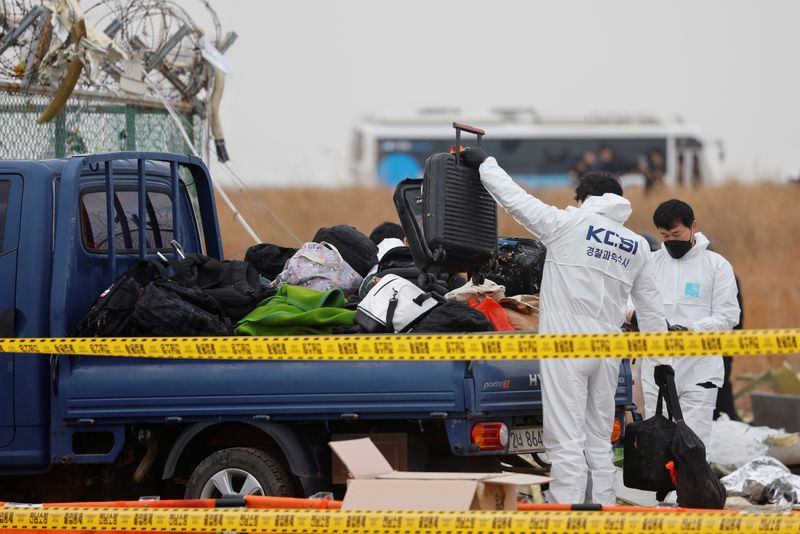 © Reuters. People work at the site where an aircraft went off the runway and crashed at Muan International Airport, in Muan, South Korea, December 30, 2024. REUTERS/Kim Soo-hyeon