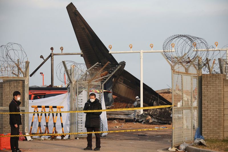 © Reuters. People stand at the site where a plane skidded off the runway and crashed at Muan International Airport in Muan, South Korea December 30, 2024. REUTERS/Kim Hong-Ji