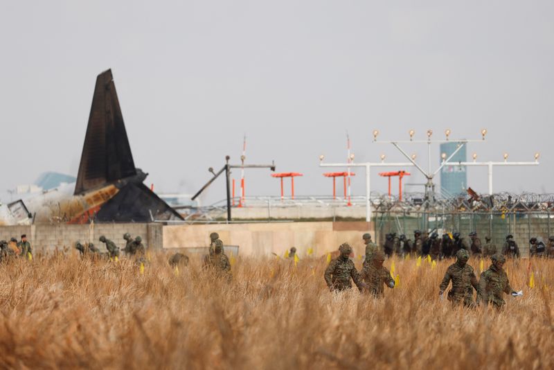 © Reuters. Military personnel work at the site where a plane left the runway and crashed at Muan International Airport in Muan, South Korea December 30, 2024. REUTERS/Kim Soo-hyeon