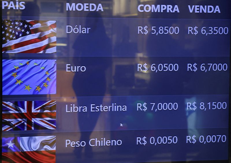 &copy; Reuters. Una donna si specchia su uno schermo che mostra il tasso di cambio del dollaro reale e di diverse valute estere a Rio de Janeiro, Brasile, 26 dicembre 2024. REUTERS/Ricardo Moraes