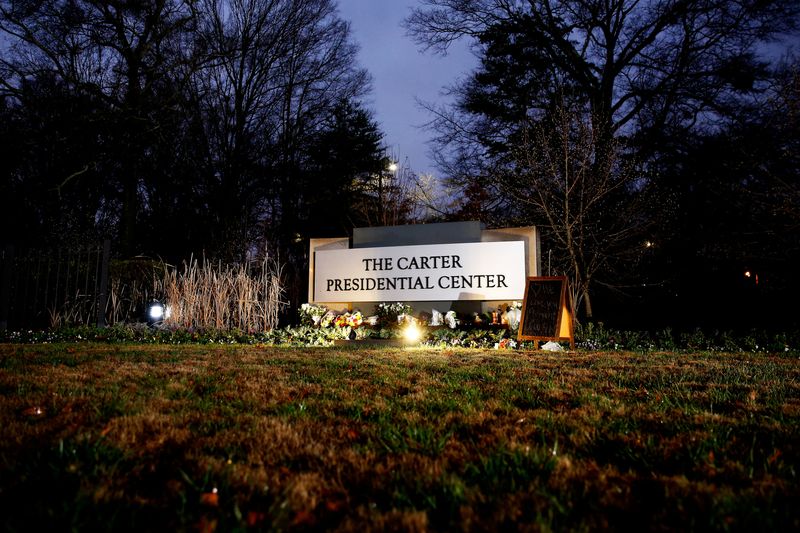 © Reuters. Flowers and memorials rest at The Carter Presidential Center sign, paying tribute to the life and legacy of former US President Jimmy Carter, who has died aged 100, in Atlanta, Georgia, U.S. December 30, 2024. REUTERS/Octavio Jones