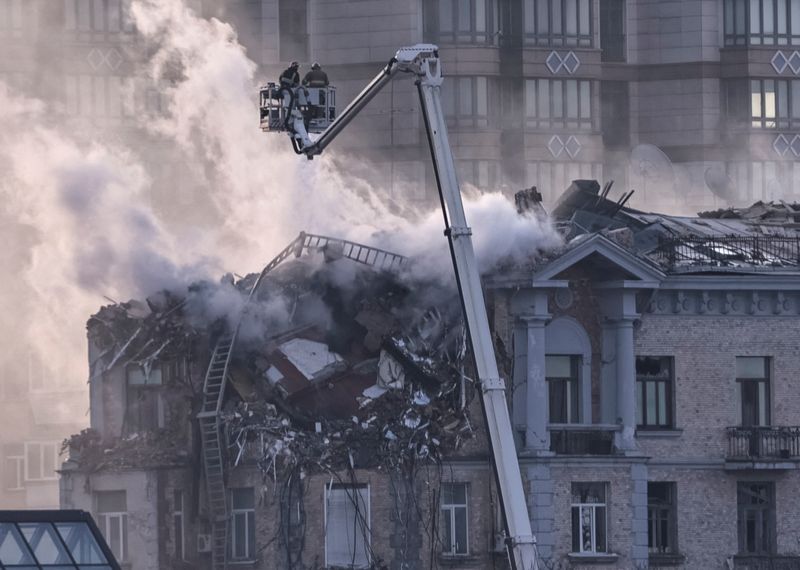 © Reuters. Firefighters work at a site of a building damaged during a Russian drone strike, amid Russia's attack on Ukraine, in central Kiev, Ukraine January 1, 2025. REUTERS/Yan Dobronosov