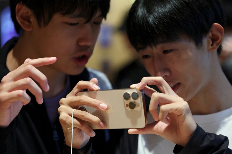 &copy; Reuters. FILE PHOTO: People check an iPhone 16 Pro as the new iPhone 16 series smartphones go on sale at an Apple store in Beijing, China September 20, 2024. REUTERS/Florence Lo/File Photo